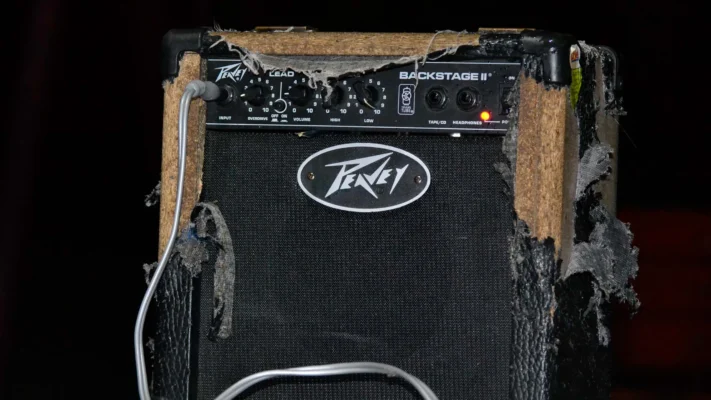 Close-up of a worn-out Peavey guitar amplifier with torn fabric and frayed edges.