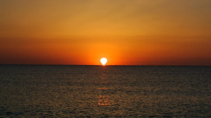 Sunrise over the sea with warm orange tones spreading across the horizon.