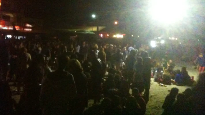 Large nighttime crowd on the sand under a bright floodlight.