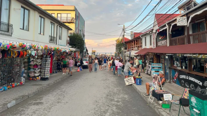 Crowds of tourists walk along the market street filled with stalls and bars.