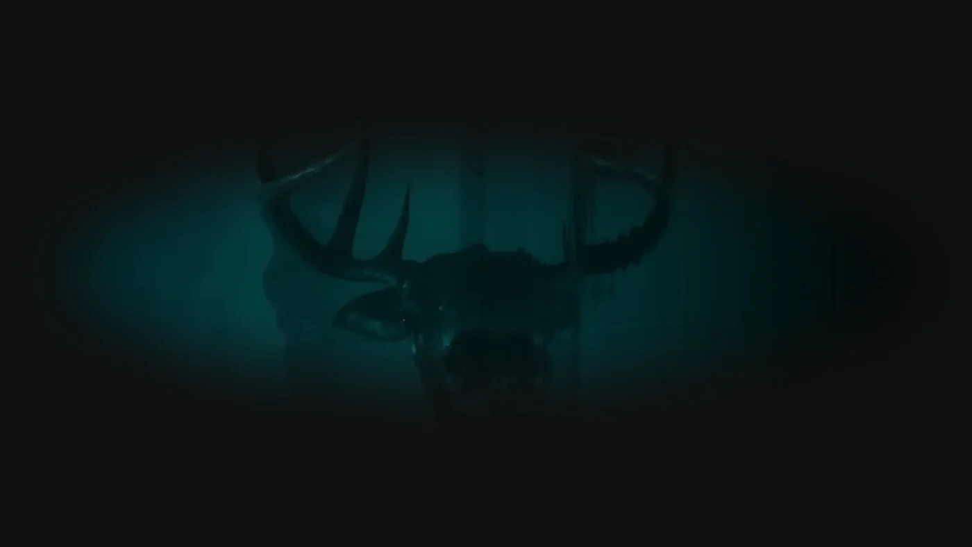 A dark, eerie shot of a deer’s head with glowing eyes and large antlers, emerging from the water - photo taken vertically.