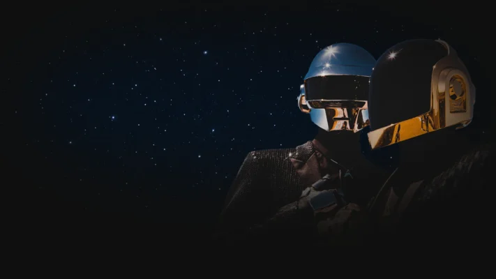 Daft Punk in chrome and gold helmets, standing together against a starry night sky.