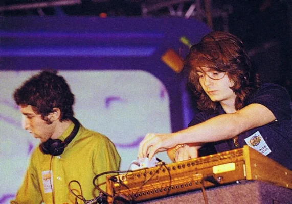 Daft Punk performing live in the 1990s with headphones and analog equipment, no helmets.