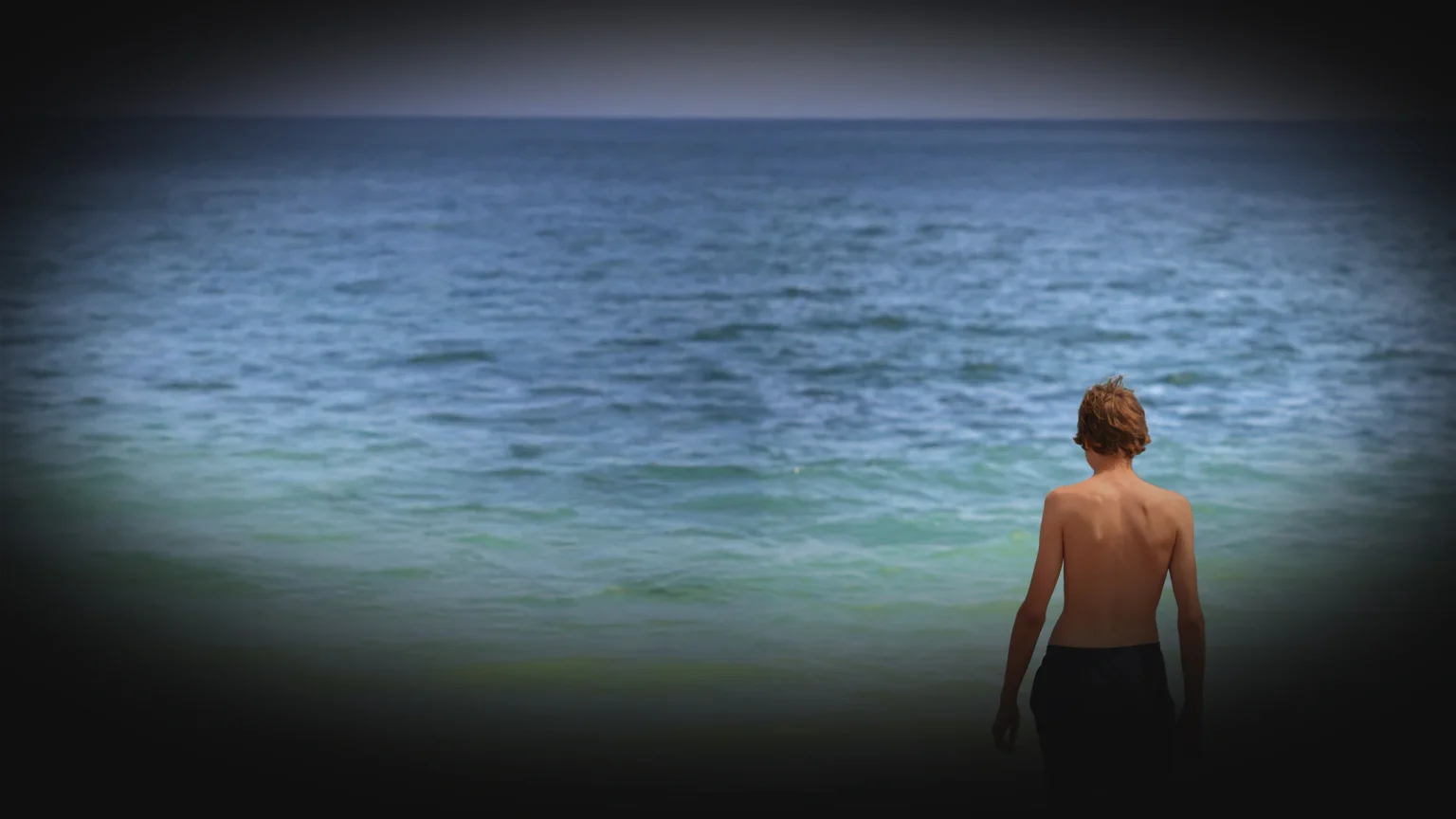 Teenager at Vama Veche beach, standing before the Black Sea horizon.