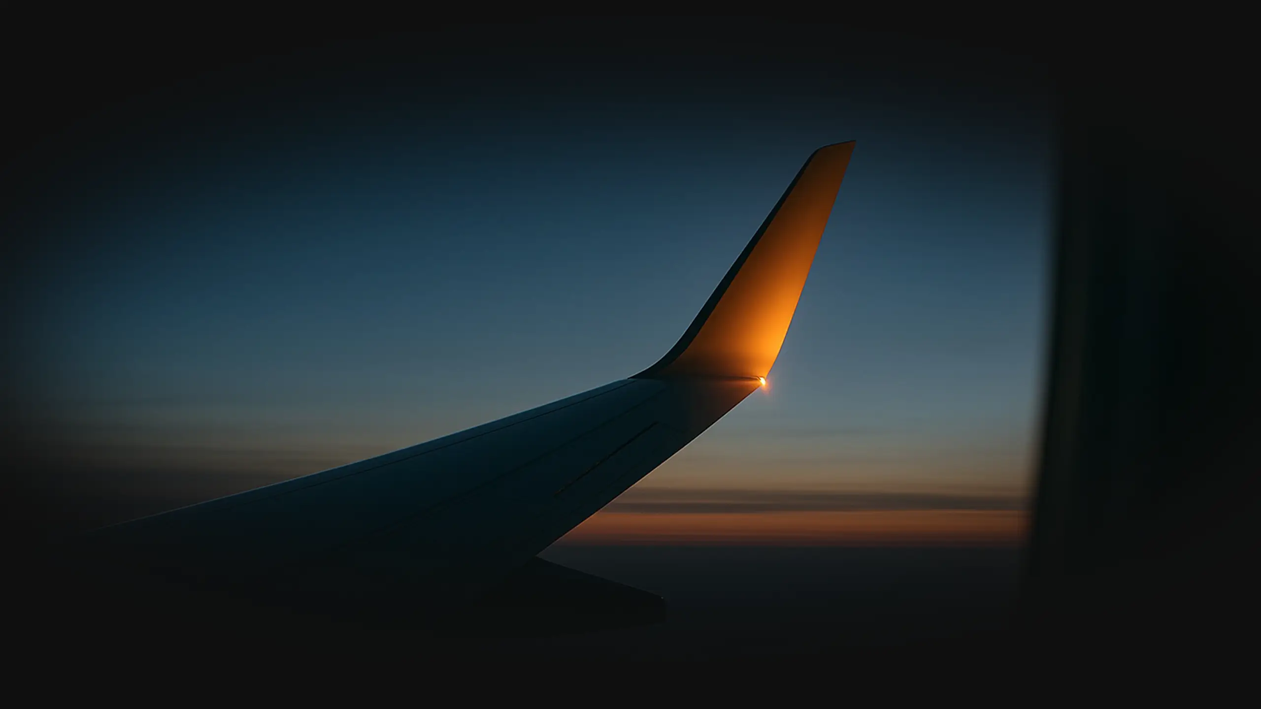 Airplane wing glowing at twilight above soft clouds, faint stars emerging in the darkening sky - symbol of distance within connection.