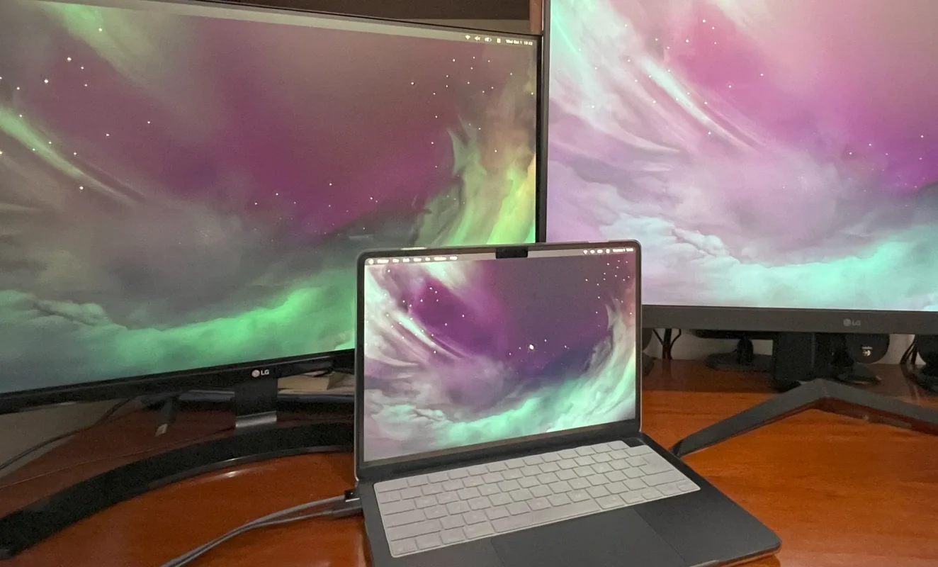 MacBook Air M4 connected to two external LG monitors, running macOS with a nebula wallpaper across all three screens.