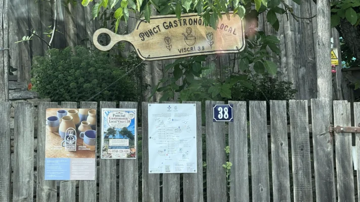 Wooden sign for the local gastronomic point at Viscri 38, mounted on a rustic fence.
