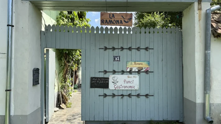 Wooden entrance gate to a local gastronomic point at Viscri 143, marked La Ramona.