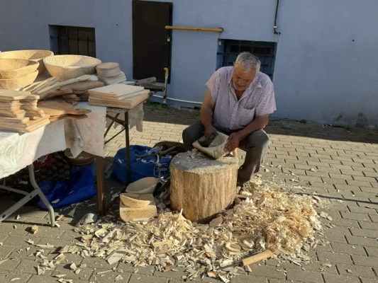 Traditional woodcarver shaping a wooden bowl by hand in Biertan, Transylvania