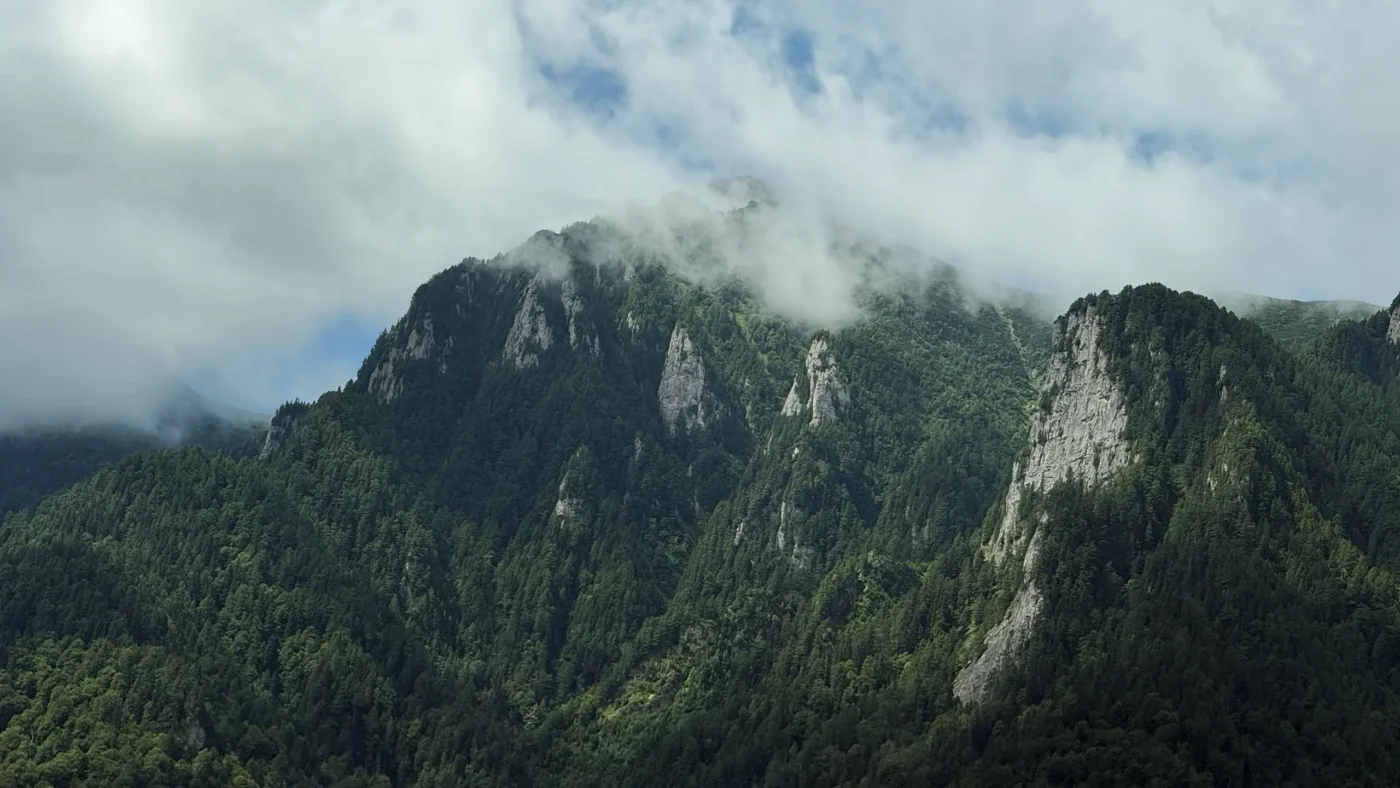 Bucegi Mountains rising through low summer clouds above the Prahova Valley in Romania.