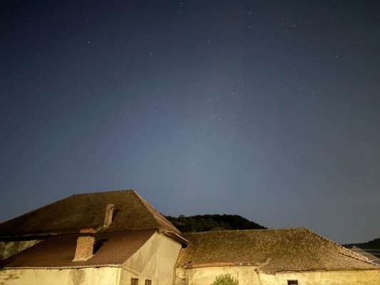 Old tiled rooftops in Cund beneath a dense field of stars at night.