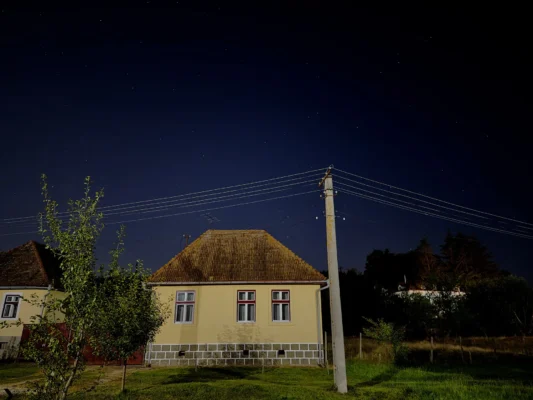 Traditional house in Cund beneath a clear star-filled night sky and overhead utility lines.