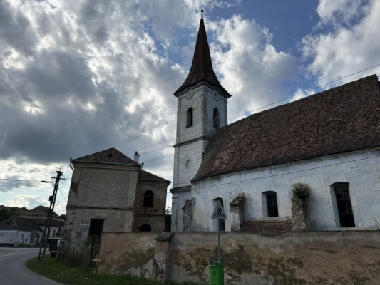 Abandoned fortified church of Cund, Transylvania, beneath dramatic summer clouds.