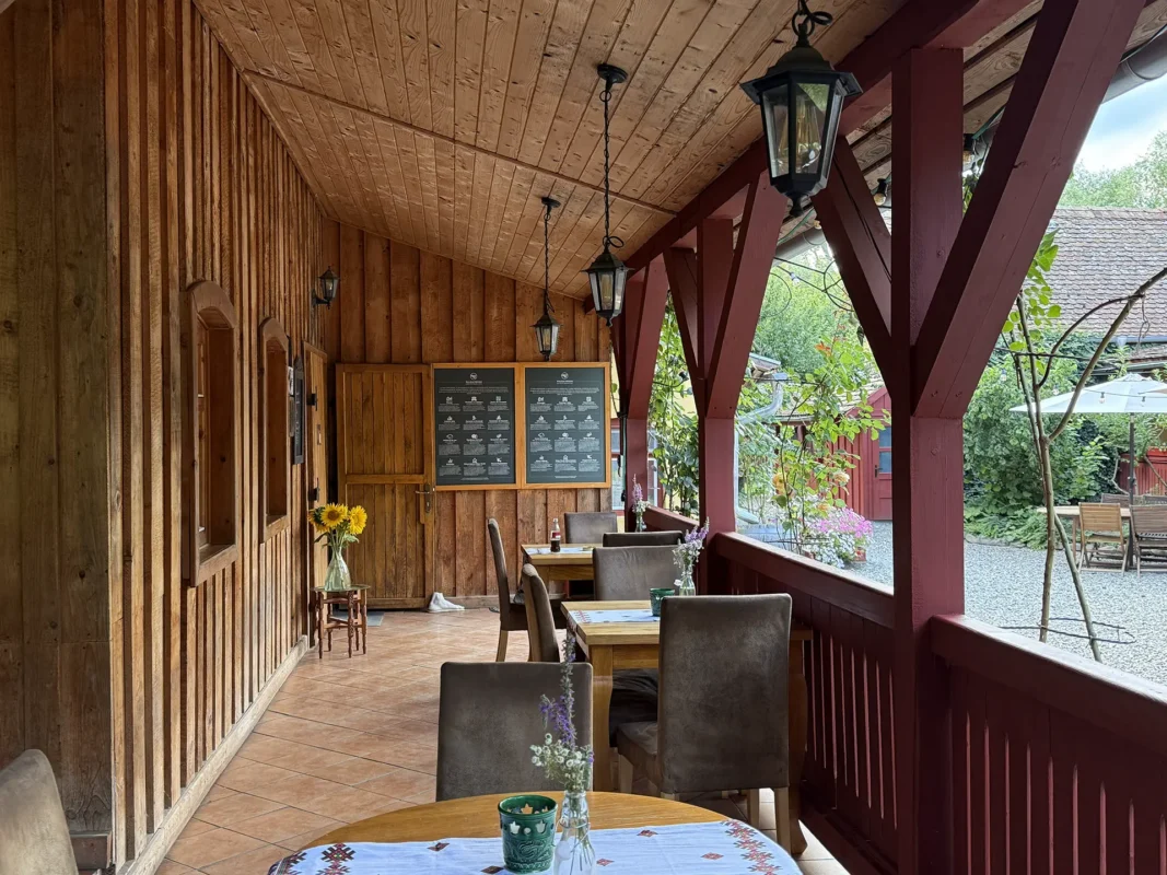 Wooden breakfast veranda at Valea Verde Retreat in Cund, with tables, flowers and traditional timber details.
