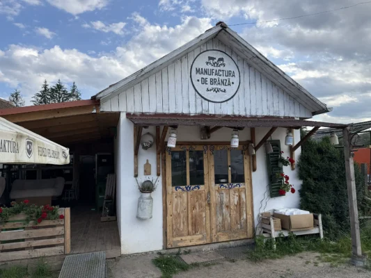Traditional cheese workshop in Cund marked "Manufactura de Brânză," with wooden doors and rustic decorations.