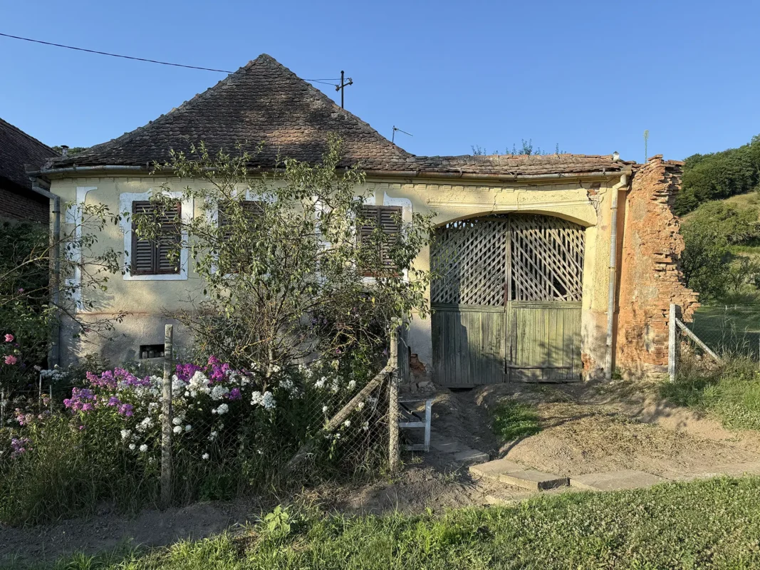 Weathered traditional house in Cund with exposed brickwork, damaged plaster and an old tiled roof.