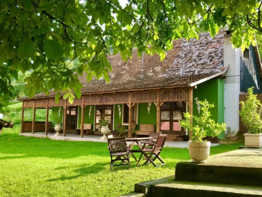 Restored traditional Saxon house at Valea Verde in Cund, Transylvania, with a wooden veranda and garden.