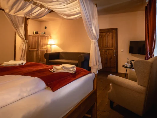 Restored guest room at Valea Verde in Cund, with traditional wooden furniture and a four-poster bed.