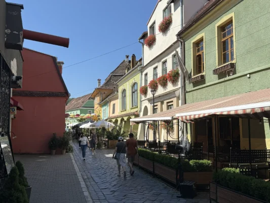 Cobblestone street lined with colourful historic houses and restaurants in Sighișoara Citadel
