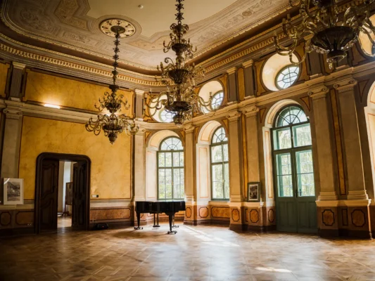 Grand reception hall at Teleki Castle in Gornești, with chandeliers, stucco decoration and arched windows