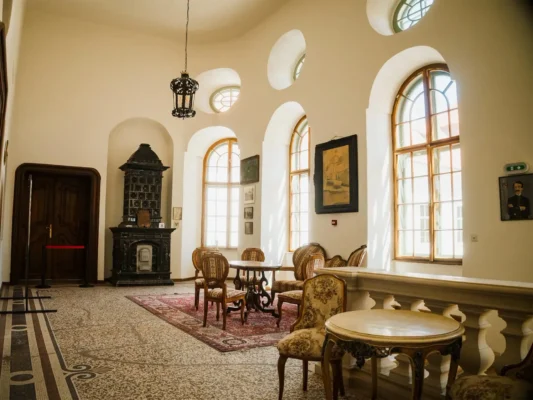 Historic sitting room at Teleki Castle in Gornești, furnished with period chairs and a tiled stove.