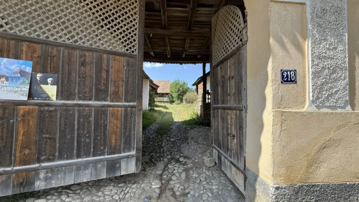 Traditional wooden gateway at a historic Saxon house in Viscri, opening onto a cobbled courtyard.