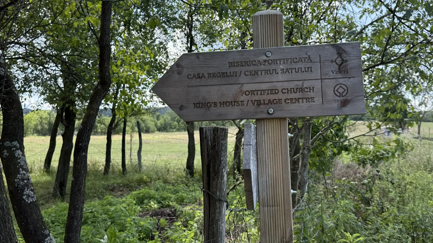 Wooden sign in Viscri pointing toward the fortified church, King's House and village centre.