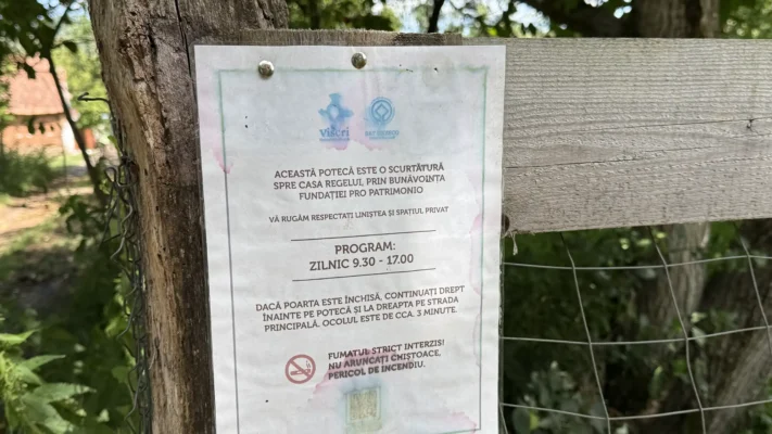 Visitor notice beside a wooded footpath in Viscri, marking a shortcut toward the King's House through private property.